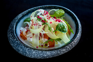 A crafted fennel salad showcases fresh greens and sweet flavors in a dark atmosphere