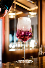 A colorful cocktail is poured into a stylish glass, celebrating a lively bar moment