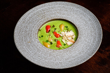 A vibrant green soup topped with colorful vegetable garnishes creates a delightful meal