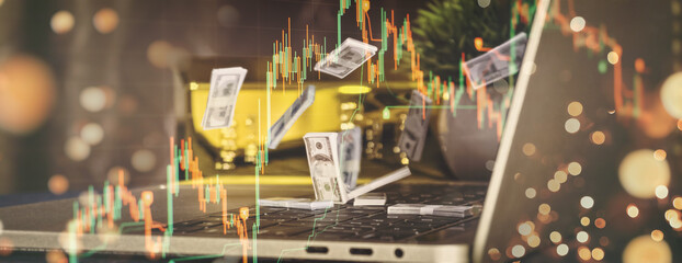 Workspace for investment and profit in financial market with scattered money, candlestick chart on laptop, gold bars,
