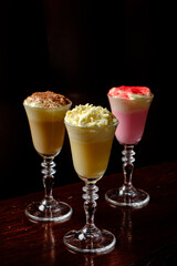 Three elegant dessert drinks in tall glasses, enticing with rich colors and textures