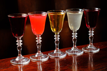 Five vibrant cocktails in elegant glasses await your enjoyment at a polished wooden bar