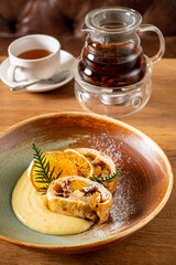 Delightful pastry with fruit and cream on a rustic plate beside a steaming cup of tea