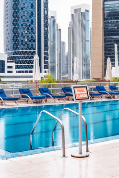 Dubai. A closed pool sign stands prominently in the early morning light, surrounded by a tranquil setting in Dubai.