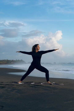 Woman practicing yoga at beach against clear sky during sunset