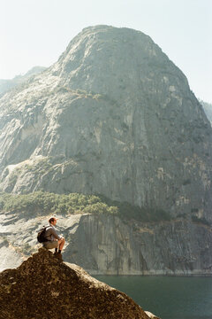 Hiker Resting on a Rock Overlooking Alpine Lake