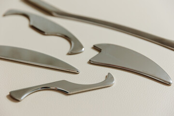 Intelligent stainless steel IASTM instruments for soft tissue massage and pain relief, the instruments lie on a beige massage table
