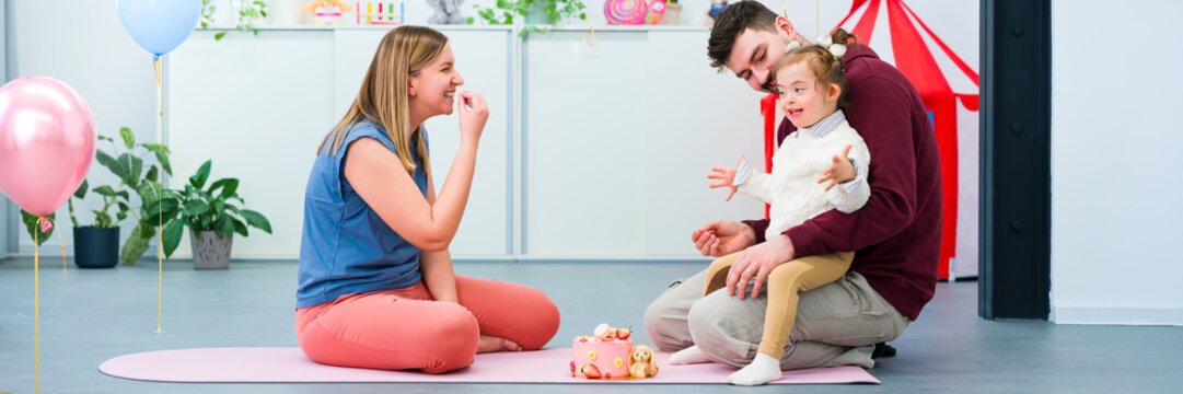 Nonverbal child with Down syndrome learning baby sign language with the help of a speech therapist and her father. Neurodiversity, learning difficulty, developmental disability.