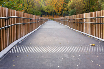 Path through the park with autumn background and wooden railings