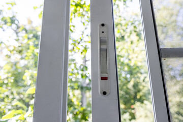 Close-up of a double-glazed balcony frame with a latch and fastening for safe ventilation. Single-sided window handle. House door and window repair concept