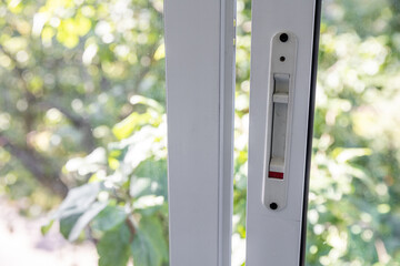 Close-up of a double-glazed balcony frame with a latch and fastening for safe ventilation. Single-sided window handle. House door and window repair concept