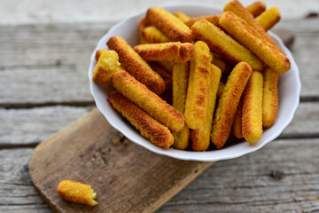 Vegetarian italian cheese breaded  oven baked  mozzarella sticks with  fresh basil on wooden background.Italian street food.