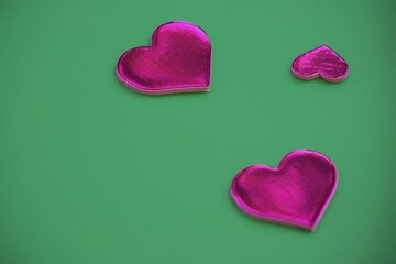 Two large and one small pink decorative hearts on a green background.