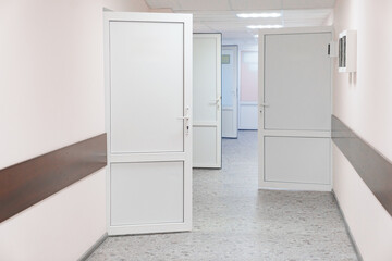 A bright corridor with open white doors. hospital premises.