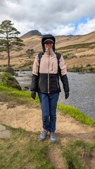Naklejka premium Beautiful woman backpacker in hooded jacket hiking at river Erriff near Aesleagh, county Mayo, Ireland, Irish landscape, mountains and nature background 