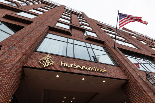 Boston, MA, USA - Dec 24, 2020 - The Four Seasons Hotel entrance in Boston, with its gold signage and an American flag waving above the brick facade