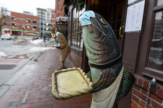 Boston, MA, USA - Dec 24, 2020 - A fish sculpture wearing a face mask stands outside a restaurant in an empty Boston street during the COVID-19 pandemic, highlighting the era&rsquo;s impact on businesses