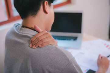 Neck ache concept. Young man sitting at office desk feeling hurt having pain in his neck.Man...