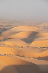 Sand dunes of Liwa desert in fog during sunrise hours.