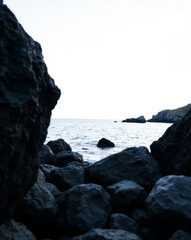 Fototapeta premium dark rocks and calm ocean: a serene coastal scene