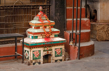 A small Buddhist temple outside a building in the street