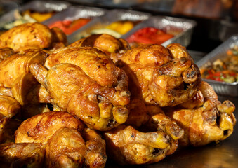 Juicy roast chickens on a tray for sale at the food market. Delicious food