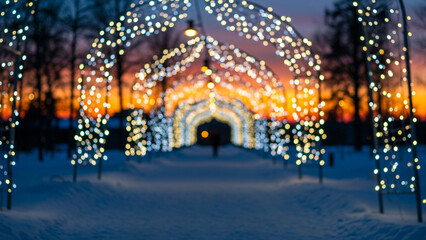 Fototapeta premium Twinkling Christmas lights adorn a snow-blanketed path as a stunning winter sunset casts its glow, establishing a whimsical and celebratory ambiance