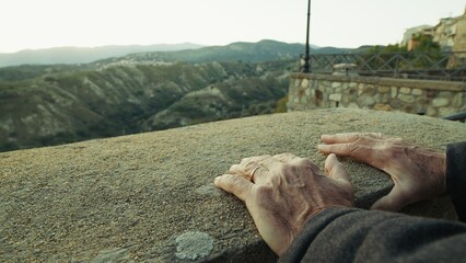 Hands Of Elderly Man Resting on a Panoramic View at Sunset At Historic Village