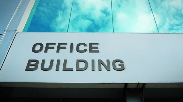 Office building sign with a reflection of the sky on glass windows, symbolizing business, professionalism, and corporate infrastructure