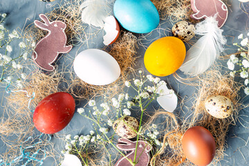 Easter background with colored eggs, feathers, sisal, rabbits and gypsophila branches on a light...