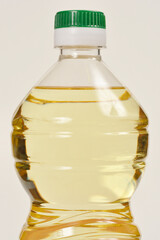 A close-up shot of a clear plastic bottle filled with yellow cooking oil, focusing on the neck and upper portion of the bottle
