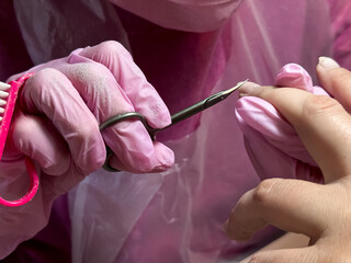 Close up of manicure process with cuticle nipper and pink gloves