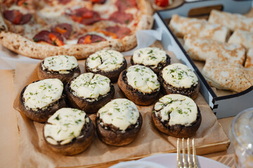 On the dining table, there is a truly tempting and inviting spread of deliciously stuffed mushrooms and gourmet pizza that has been artfully arranged for everyone to enjoy and savor at their leisure