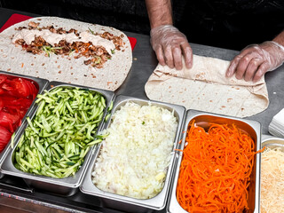 Preparing delicious wraps with fresh vegetables and meat in kitchen