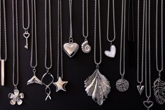 Various silver necklaces and pendants on black background