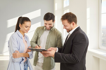 Family couple buyers signing contract document in real estate agent after buying new apartment, put...