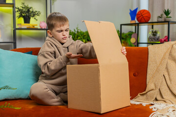 Angry dissatisfied shopper child boy unpacking parcel feeling upset and confused with wrong mistake...