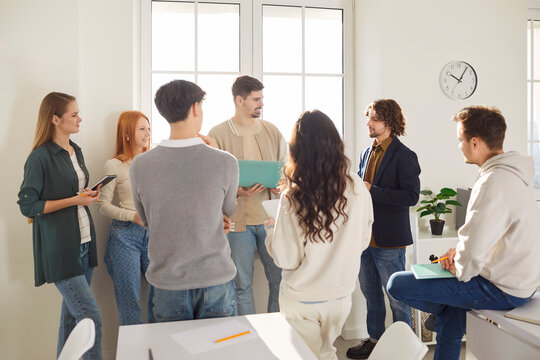 Young friends, business coworkers office group talk, students using laptop online at work, discussing project learning strategy, planning common startup, studying together, share opinions and ideas