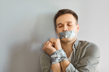 Unconscious male victim lying on the floor with tied hands and a taped mouth, representing crime,...