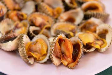Cooked cockle on plate usually serve with spicy seafood sauce, menu from sea shell. Semi-cooked raw food.