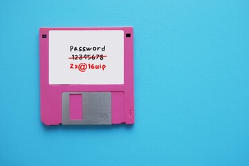 Floppy disk on blue background with very weak and easy to guess password written - replaced to strong and more secure password