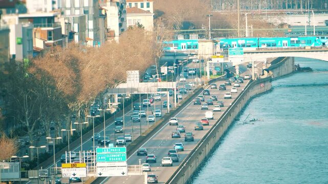 Road traffic on the busy Rhone River embankment and suburban trains in Lyon, France