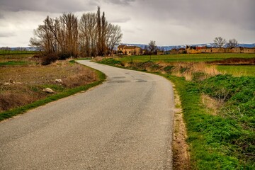 Una carretera de asfalto entre prados y tierras de cultivo.