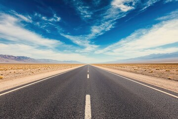Naklejka premium Empty desert road stretching toward distant mountains under a vast, cloudy sky