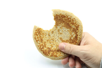 Hand showing a bitten pancake, on white background.