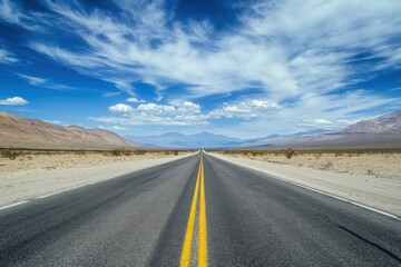 Fototapeta premium Open road leads to distant mountains under cloudy skies, travel or journey stock