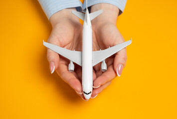 A woman holds a passenger plane in her palms, protecting it. Air travel insurance concept. Air...