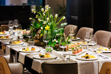 Elegant floral centerpiece with white tulips and lush greenery on a luxurious dining table