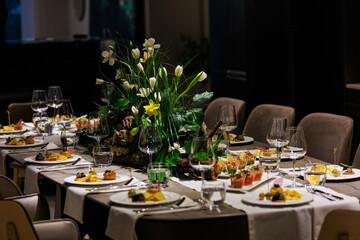 Elegant floral centerpiece with white tulips and lush greenery on a luxurious dining table