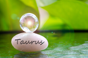 Taurus text engraved on Zen stone with shining glass marble on top. Zodiac concept